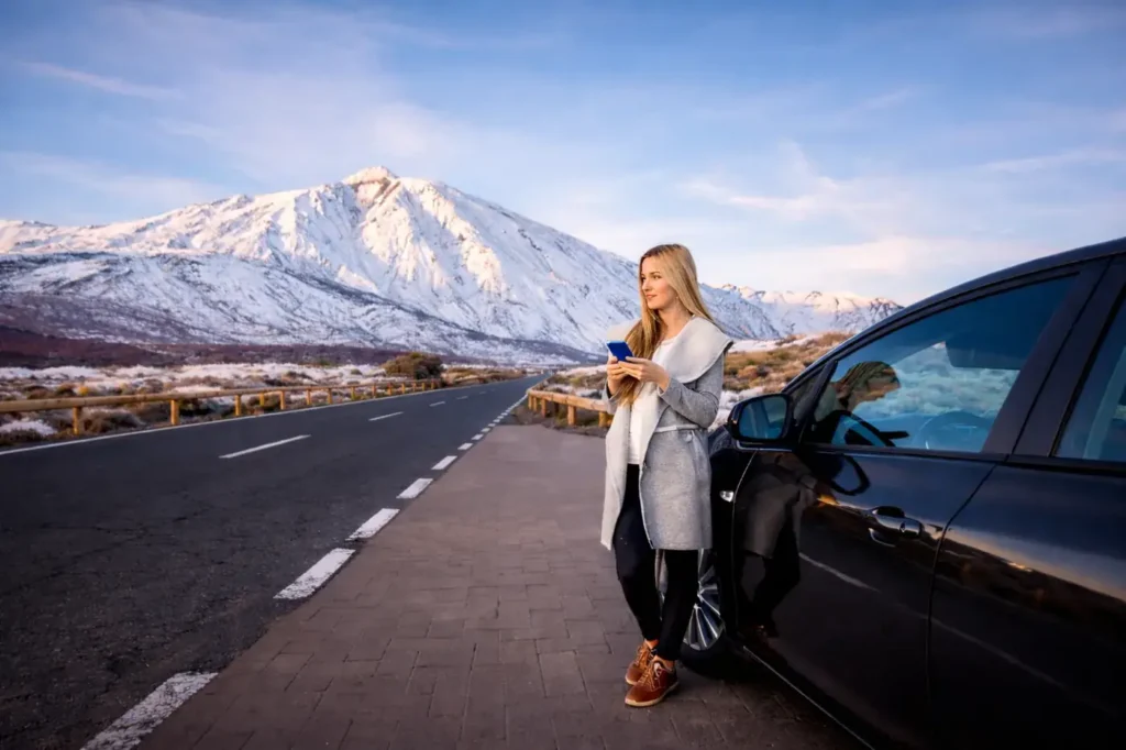 Seguro de coche en Tenerife mujer junto a coche negro con el Teide nevado